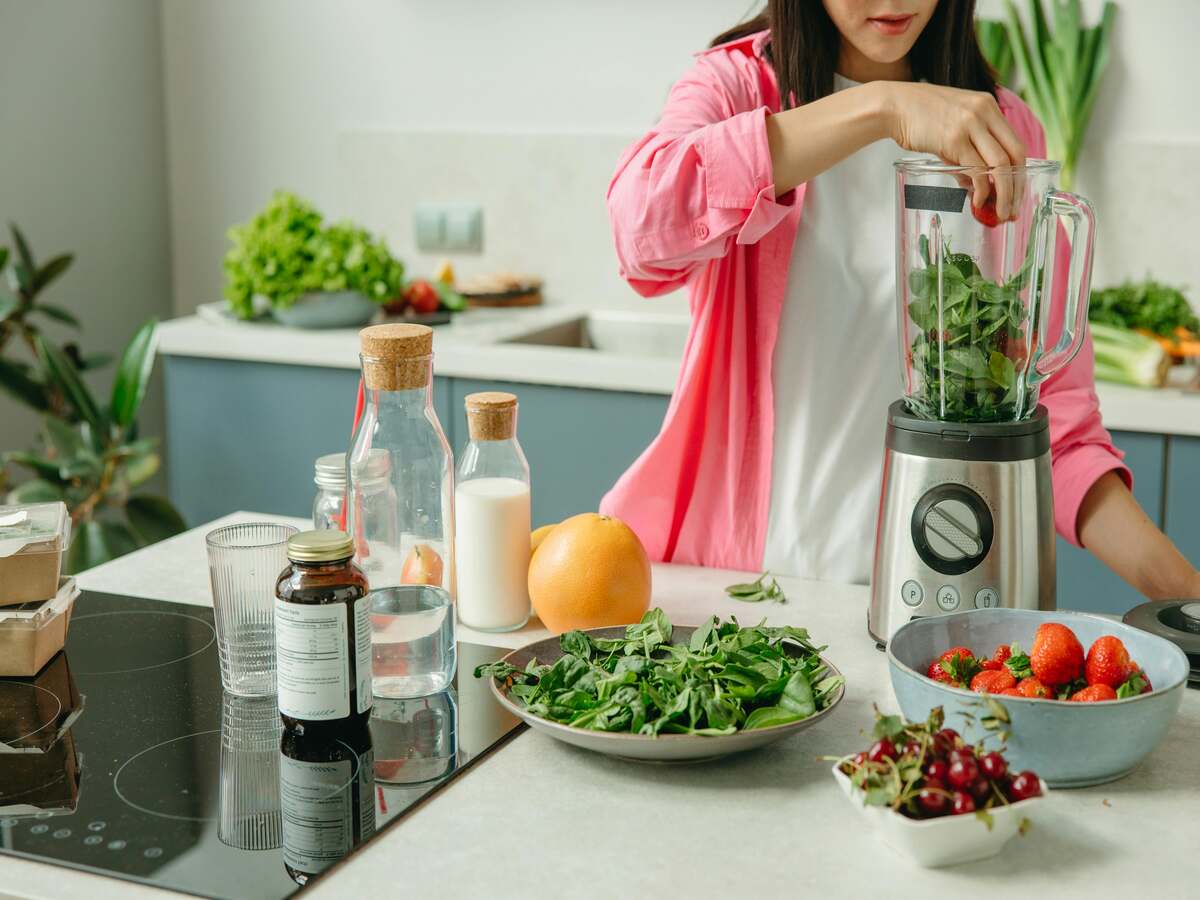 A woman using a blender on a countertop.