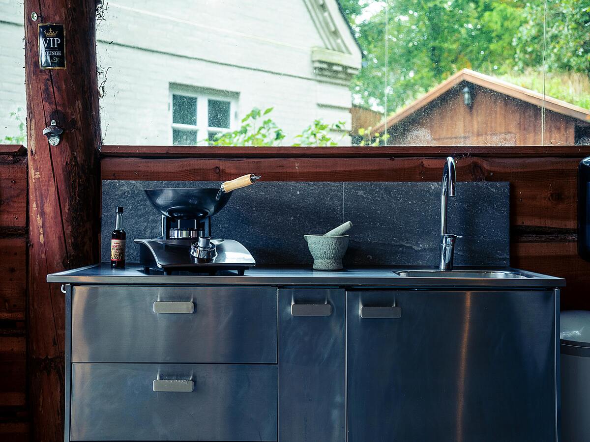 A person preparing to learn how to clean a wok that is sitting on a counter next to a bottle.