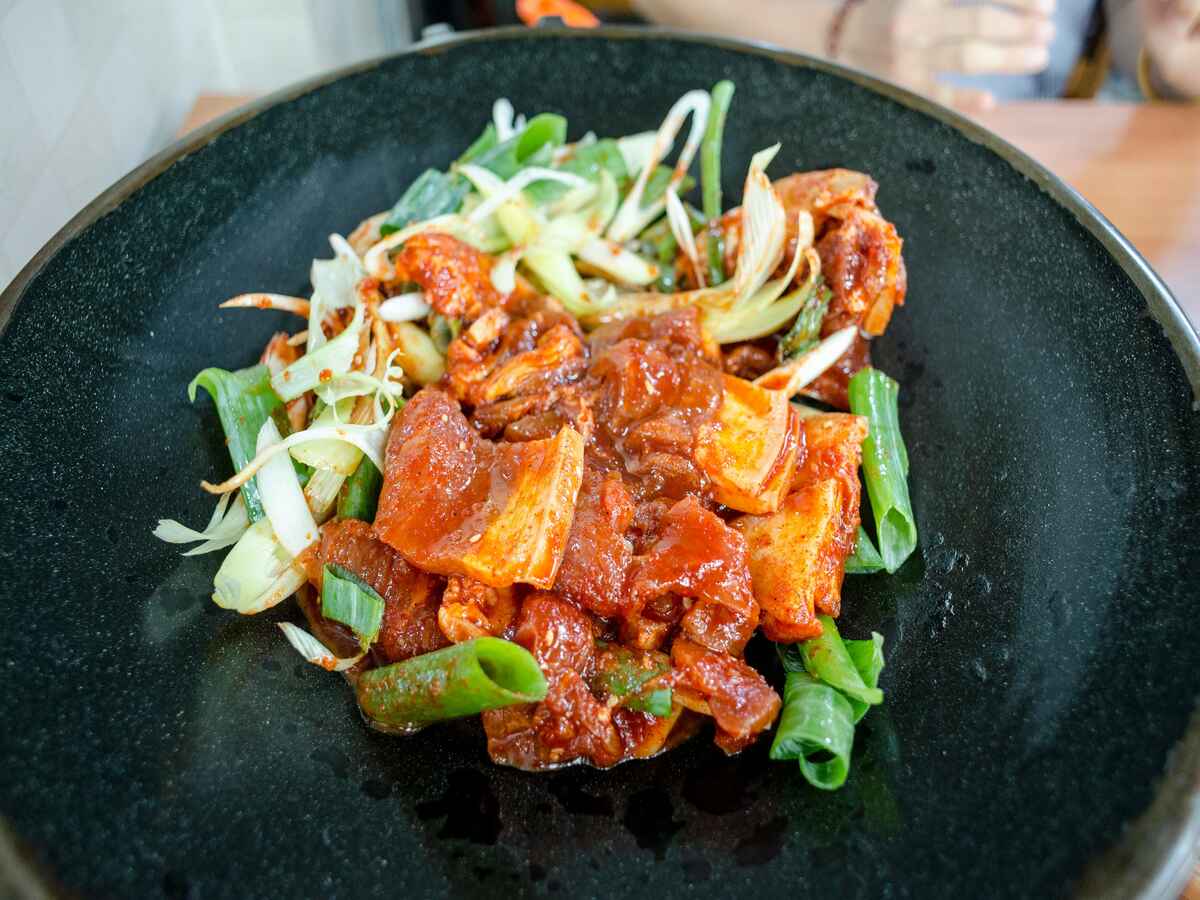 Cast iron cooking of pork and green vegetables.